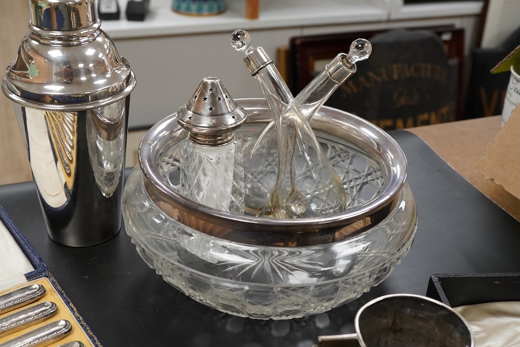 A silver christening mug, Birmingham, together with three cased sets, silver rimmed cut glass bowl, plated cocktail shaker etc